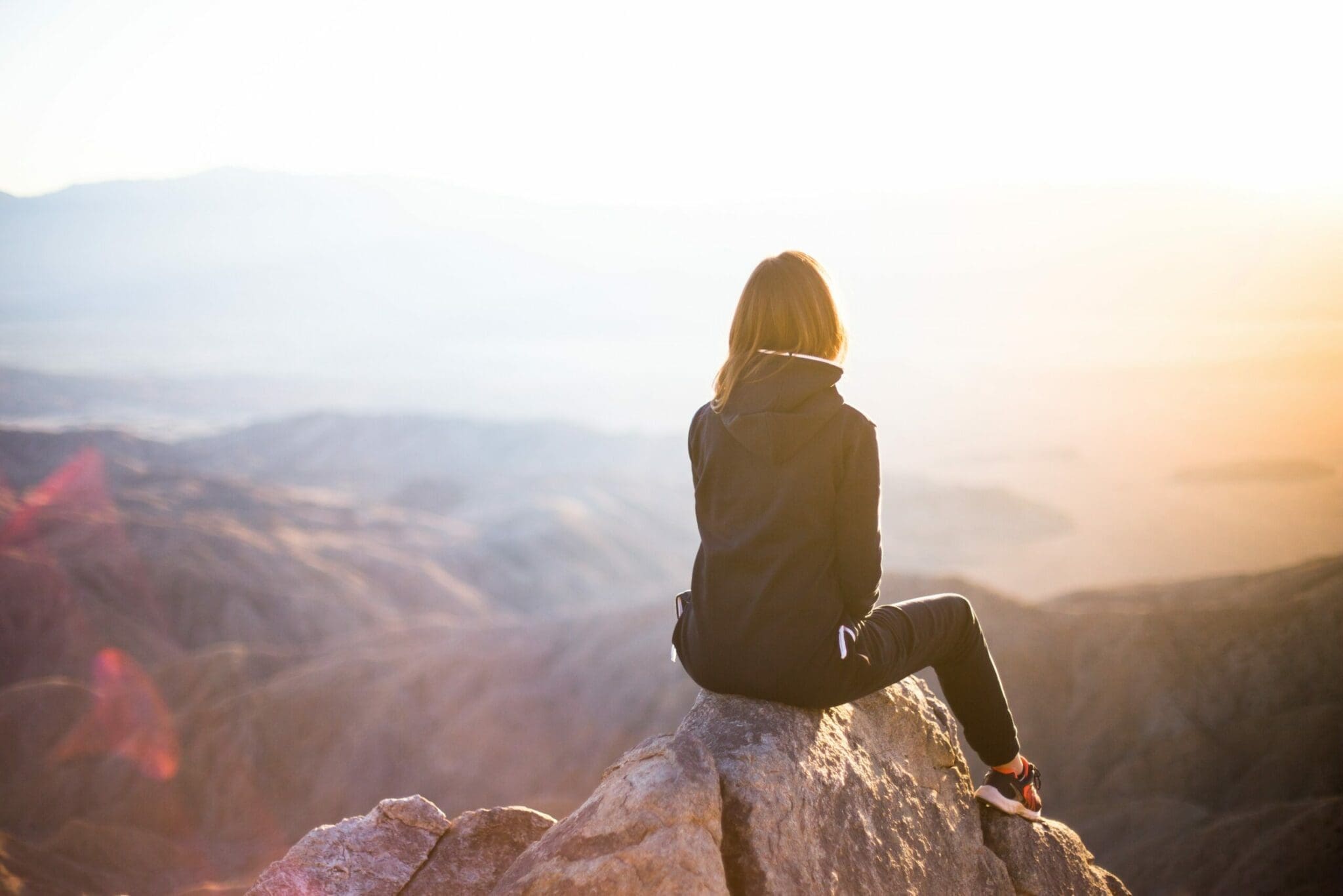 girl sitting on mountain top observing the view