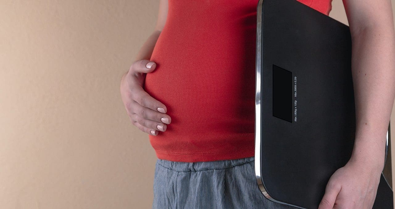 pregnant woman holding scale