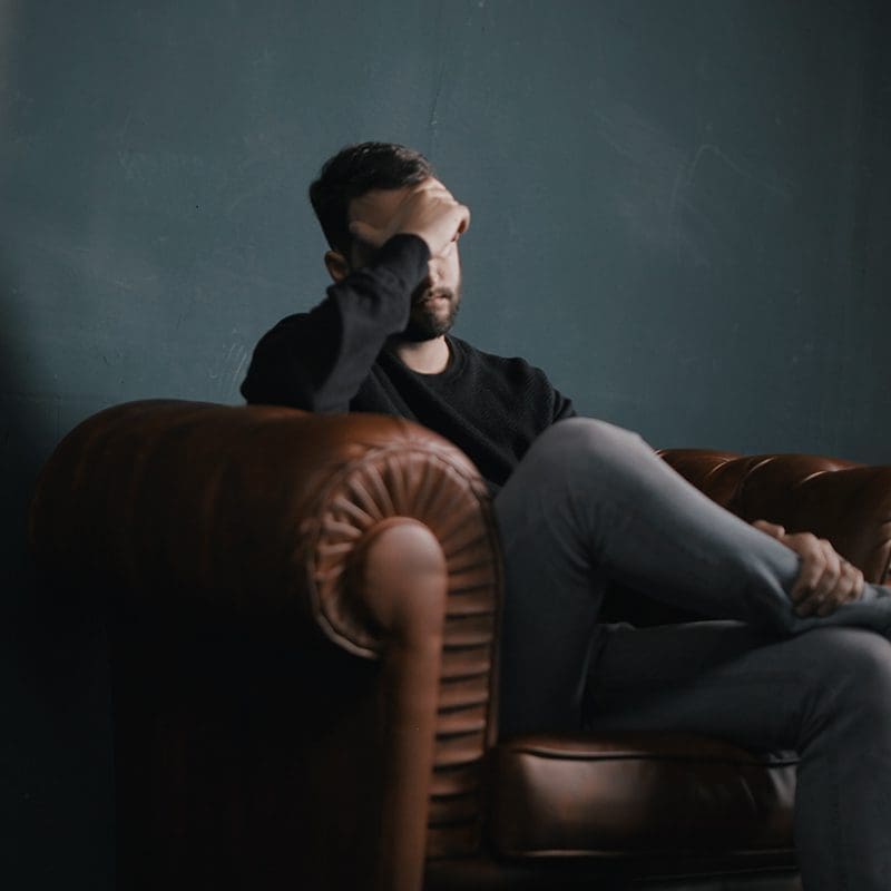 man sitting on couch depressed Man seems depressed