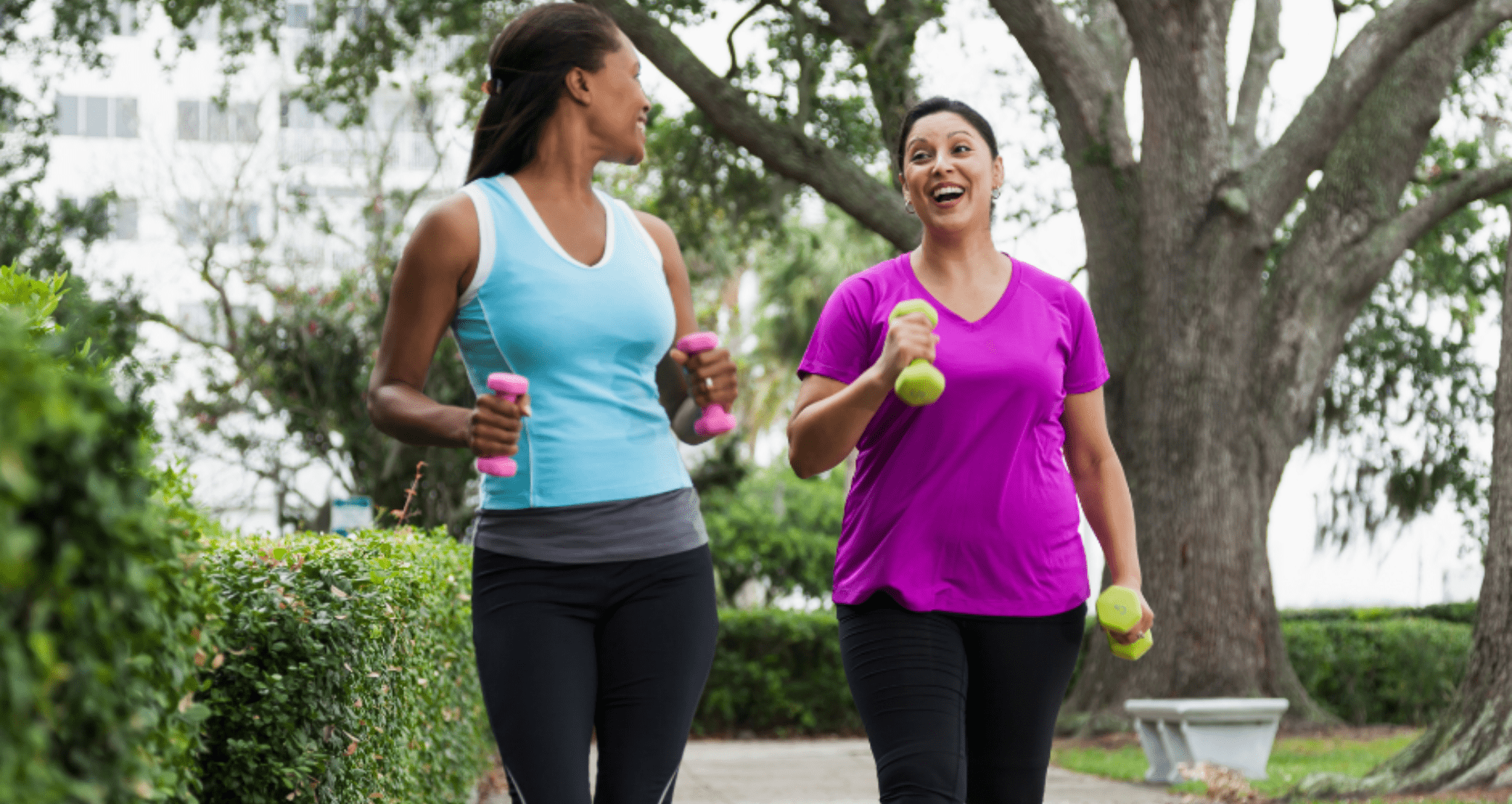 Two woman jogging while holding dumbbells