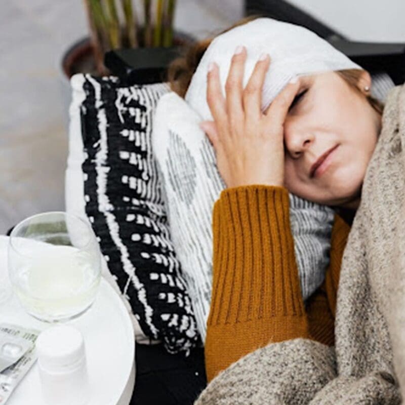 woman laying on couch with compress on head woman laying on couch with compress on head