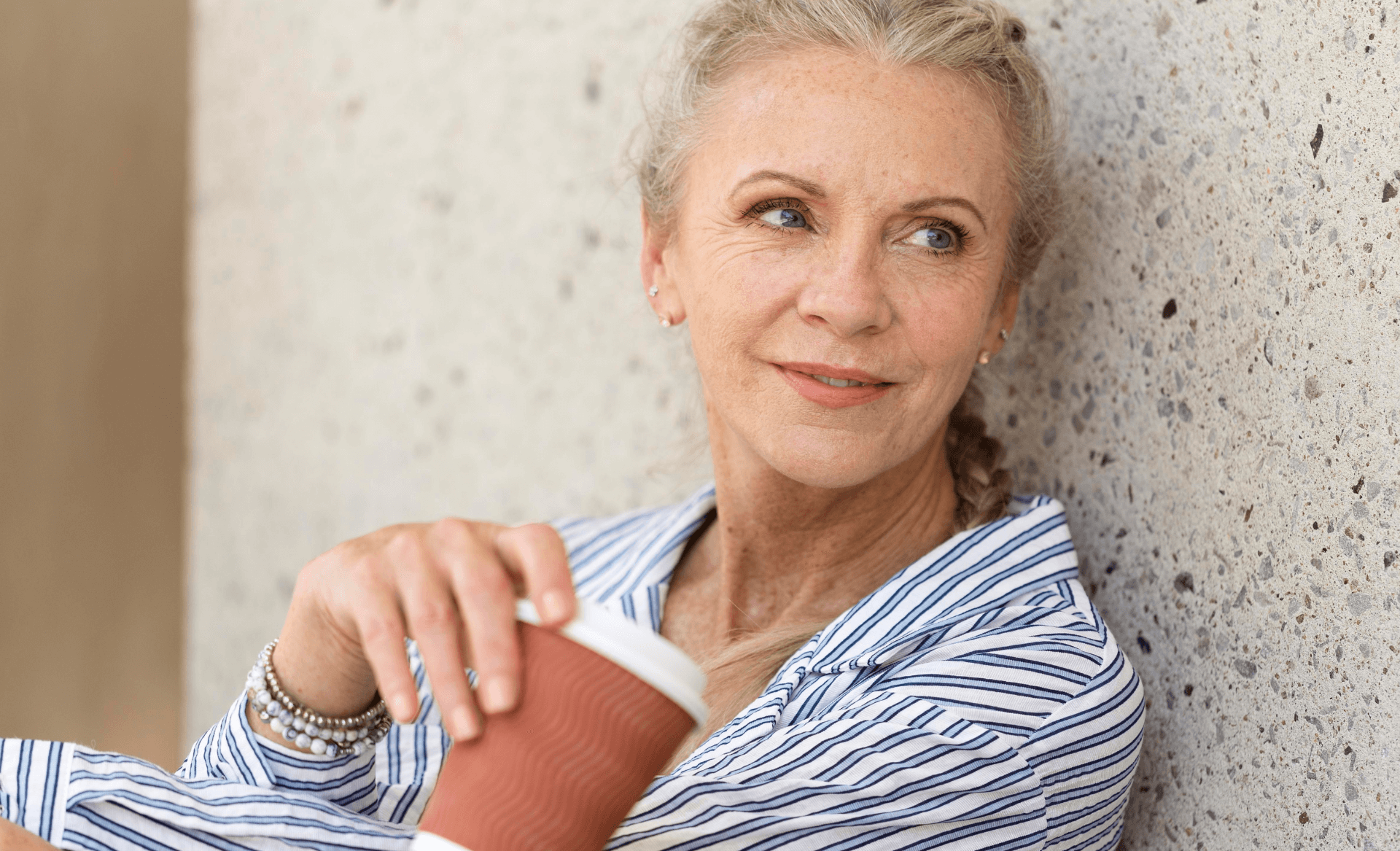 elderly woman having coffee, leaning back against wall