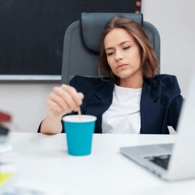 woman sitting in office drained out, stirring coffee cup woman sitting in office drained out, stirring coffee cup